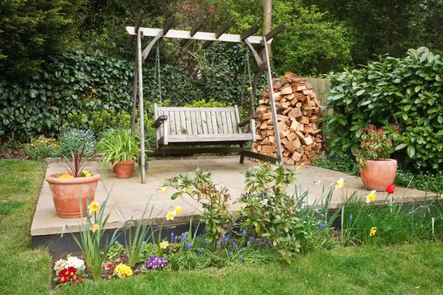 Patio swing in a garden with piles of firewood - Keep pests away from your home with Anderson Pest Solutions in IN and IL