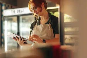 Grocery store owner looks at tablet. Contact Anderson Pest Solutions for grocery store and food retail pest management in Illinois.