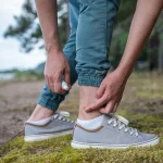 Person applying medication to a mosquito bite on their ankle