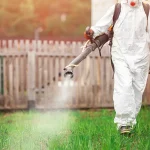 Pest control expert spraying mosquito treatment in an open field